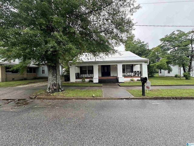 bungalow featuring a porch, metal roof, and a front yard
