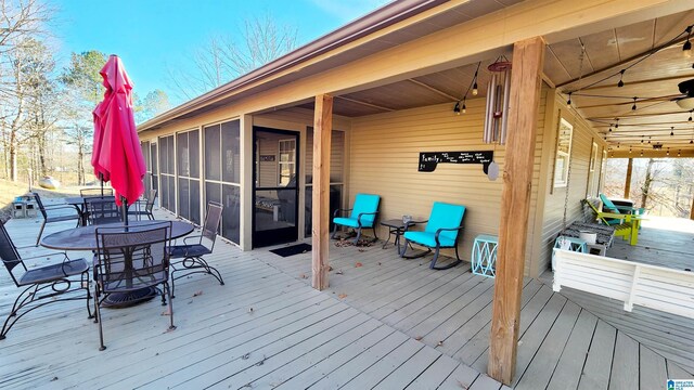 deck with a sunroom and outdoor dining space