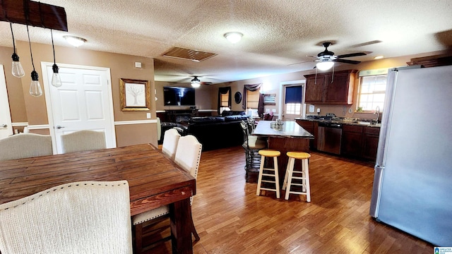 dining area featuring a textured ceiling, a ceiling fan, wood finished floors, and visible vents