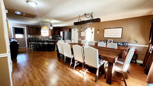 dining room with a textured ceiling, ceiling fan, and light wood-style flooring