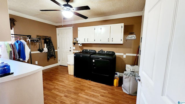 clothes washing area featuring a ceiling fan, a textured ceiling, washing machine and dryer, cabinet space, and light wood-style floors