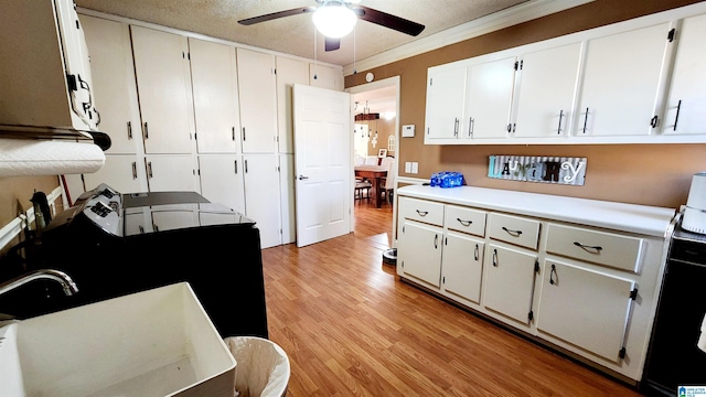 kitchen with ceiling fan, crown molding, light wood-type flooring, light countertops, and white cabinets