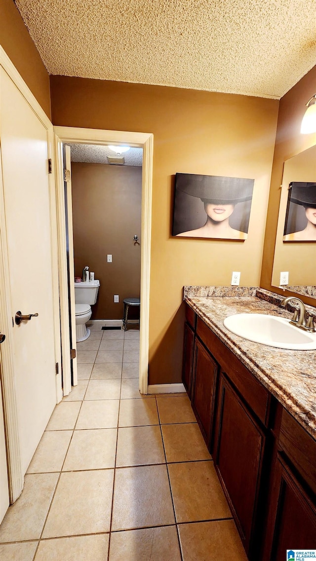 bathroom featuring toilet, a textured ceiling, tile patterned flooring, and vanity