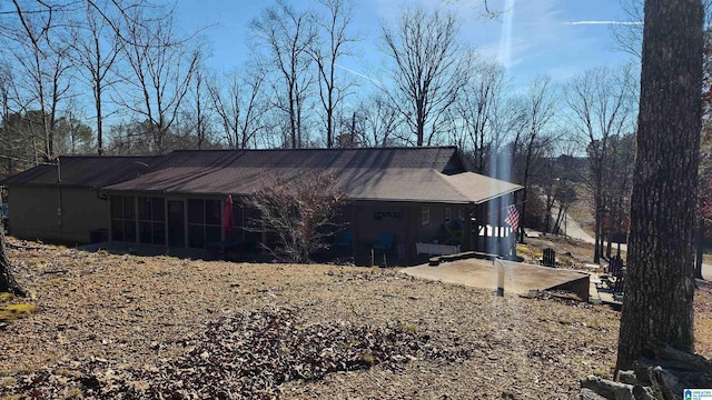 view of side of home with roof with shingles and a sunroom