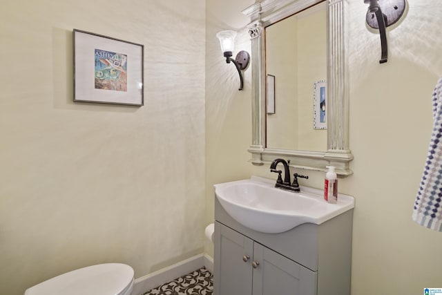 bathroom with toilet, baseboards, and vanity