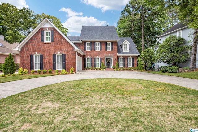 colonial inspired home with brick siding, a front yard, and curved driveway