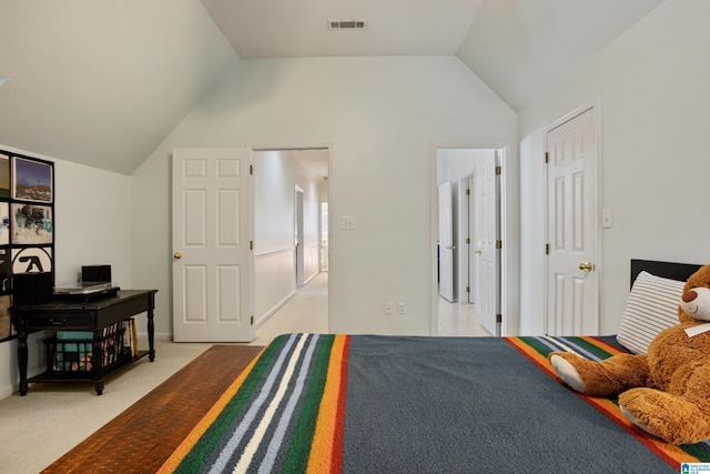bedroom featuring light colored carpet, vaulted ceiling, and visible vents