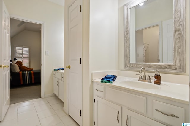 ensuite bathroom featuring vanity, connected bathroom, tile patterned floors, and vaulted ceiling