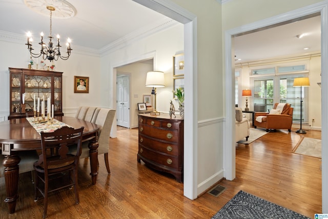 dining room featuring a chandelier, ornamental molding, and wood finished floors