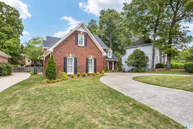 view of front of house with fence, curved driveway, a front lawn, and brick siding