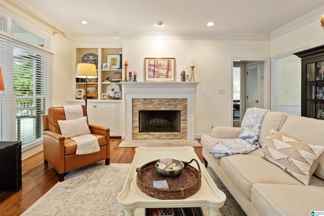 living area featuring crown molding, a fireplace, recessed lighting, and wood finished floors