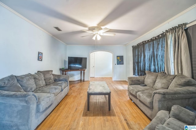 living area featuring crown molding, arched walkways, a ceiling fan, and visible vents