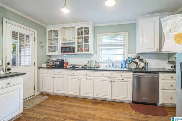 kitchen featuring black microwave, dark countertops, stainless steel dishwasher, a sink, and ornamental molding