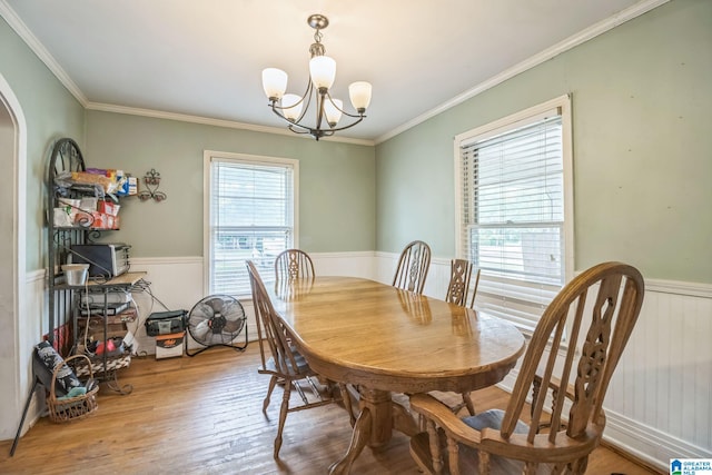 dining space featuring crown molding, wainscoting, wood finished floors, and a chandelier