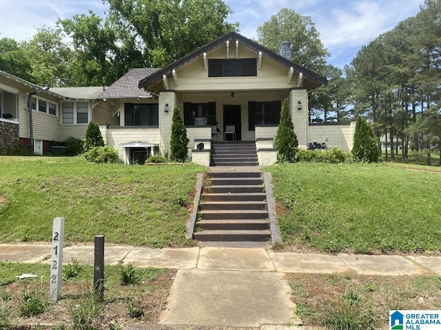 view of front of home featuring covered porch, stairs, and a front yard