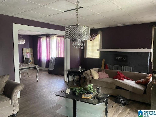 living area with a paneled ceiling, wood finished floors, and a chandelier