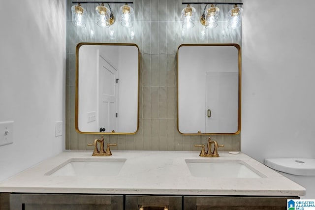 bathroom with double vanity, toilet, and a sink