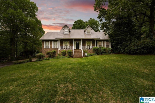 new england style home featuring a porch, metal roof, and a front lawn
