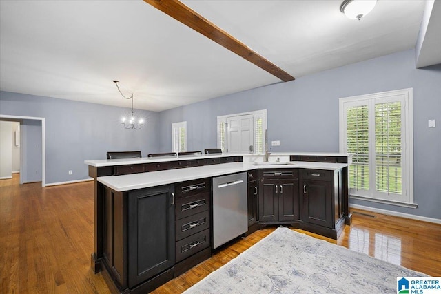 kitchen with stainless steel dishwasher, light countertops, a sink, and an inviting chandelier