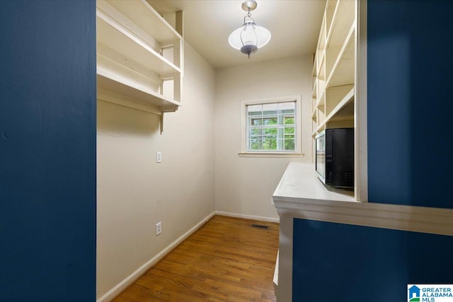interior space with baseboards, wood finished floors, and visible vents