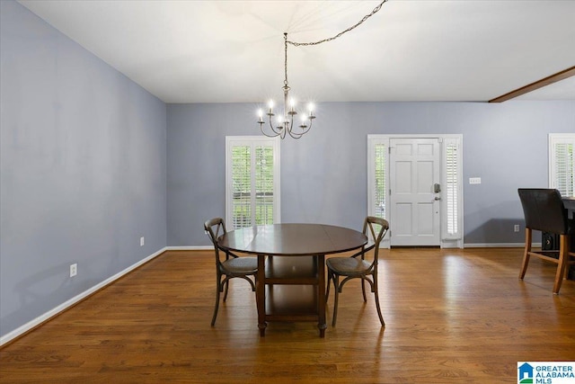 dining area featuring baseboards, a chandelier, and wood finished floors