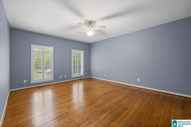empty room with baseboards, a ceiling fan, and wood finished floors