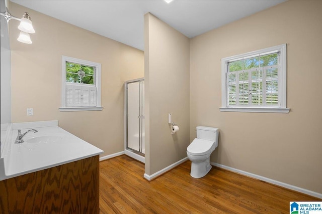 bathroom with plenty of natural light, a stall shower, wood finished floors, and toilet