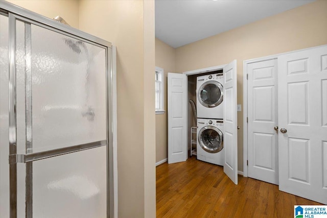 washroom featuring baseboards, laundry area, stacked washer / dryer, and wood finished floors