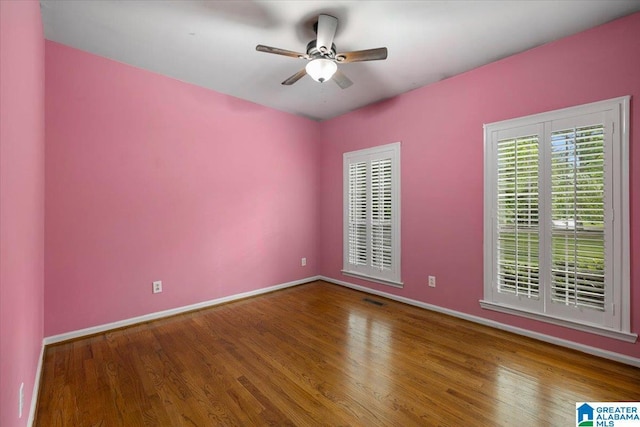 spare room featuring baseboards, ceiling fan, wood finished floors, and visible vents