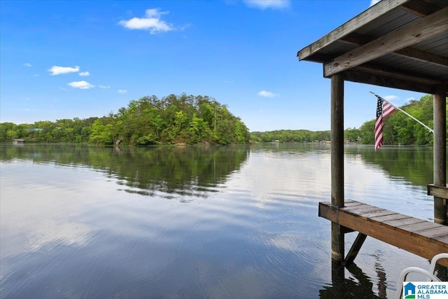 view of dock with a water view and a forest view