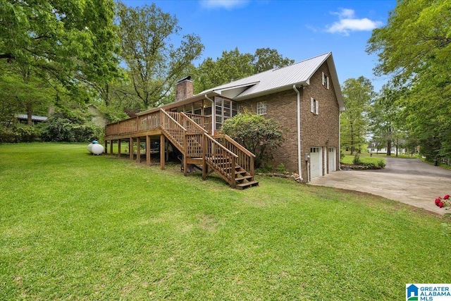 rear view of house featuring driveway, a chimney, a lawn, a garage, and stairway