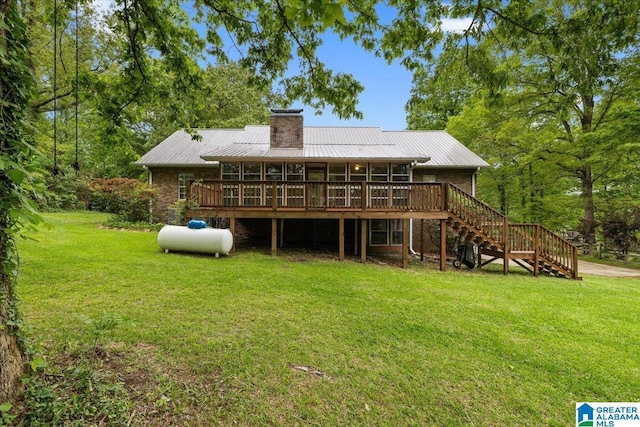 rear view of house featuring a deck, a chimney, metal roof, a lawn, and stairway