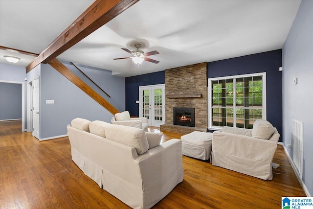 living area featuring baseboards, ceiling fan, wood finished floors, and a fireplace