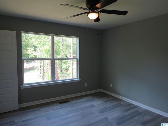spare room with plenty of natural light, ceiling fan, wood finished floors, and visible vents
