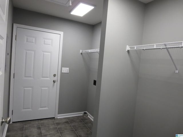 laundry room featuring dark tile patterned flooring, laundry area, and baseboards