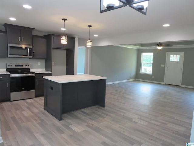kitchen featuring baseboards, recessed lighting, light countertops, light wood finished floors, and appliances with stainless steel finishes