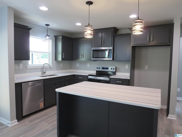 kitchen with light countertops, appliances with stainless steel finishes, a sink, and light wood-type flooring