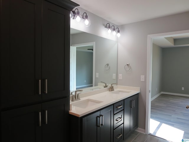 full bathroom with double vanity, baseboards, and a sink