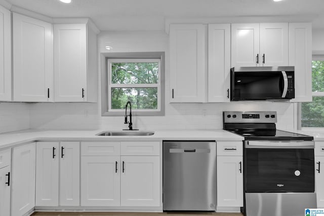 kitchen with a sink, white cabinetry, backsplash, and stainless steel appliances