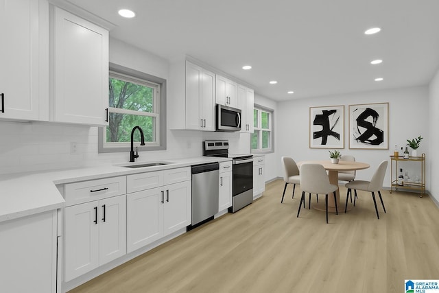 kitchen featuring a sink, stainless steel appliances, recessed lighting, a healthy amount of sunlight, and backsplash