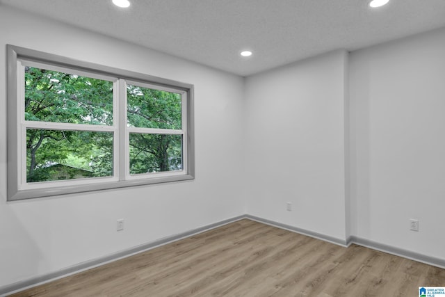 spare room featuring baseboards, recessed lighting, and light wood-style flooring