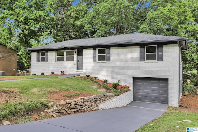 ranch-style home with brick siding, a garage, a front lawn, and driveway