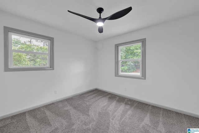 carpeted spare room featuring a ceiling fan and baseboards