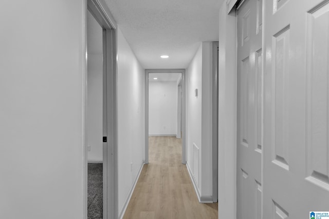 hall with baseboards, recessed lighting, light wood finished floors, and visible vents