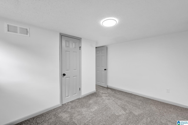 empty room featuring baseboards, carpet, a textured ceiling, and visible vents