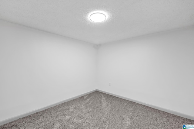carpeted spare room with a textured ceiling and baseboards