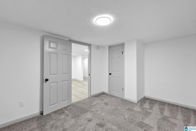 unfurnished bedroom with carpet floors, a textured ceiling, and baseboards