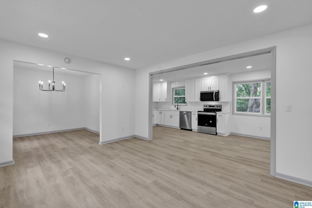 kitchen with white cabinetry, baseboards, a chandelier, stainless steel appliances, and light wood-style flooring