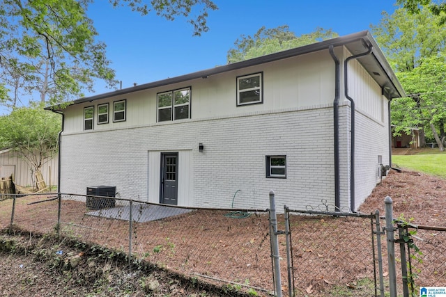 back of house with brick siding, central AC, and fence