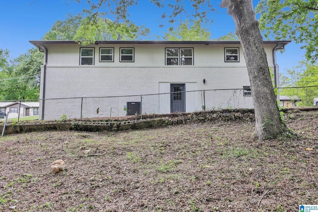 rear view of property featuring fence and brick siding